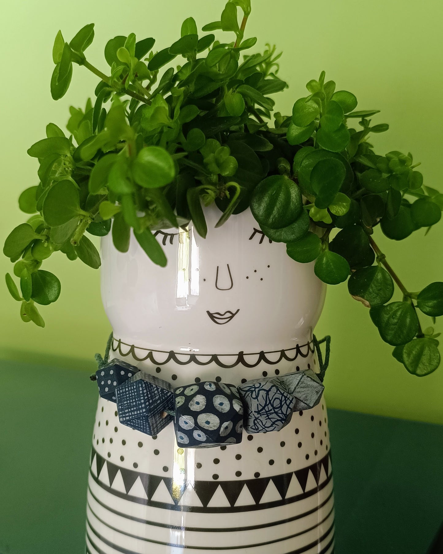 person flower pot with wooden bead necklace round it's neck